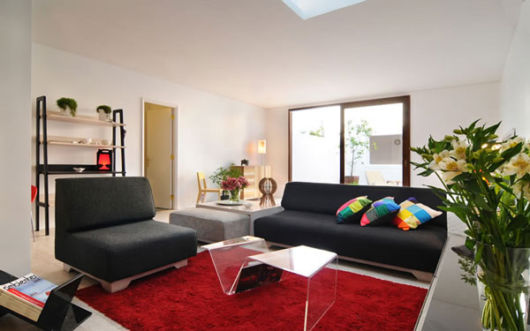 salas com sofá preto com tapete vermelho