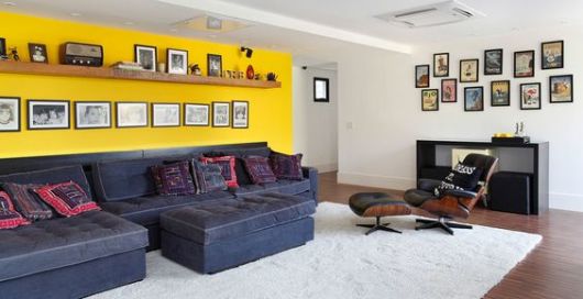 salas com sofá preto parede amarela