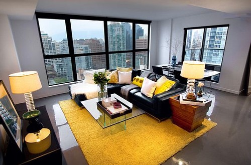 salas com sofá preto tapete amarelo
