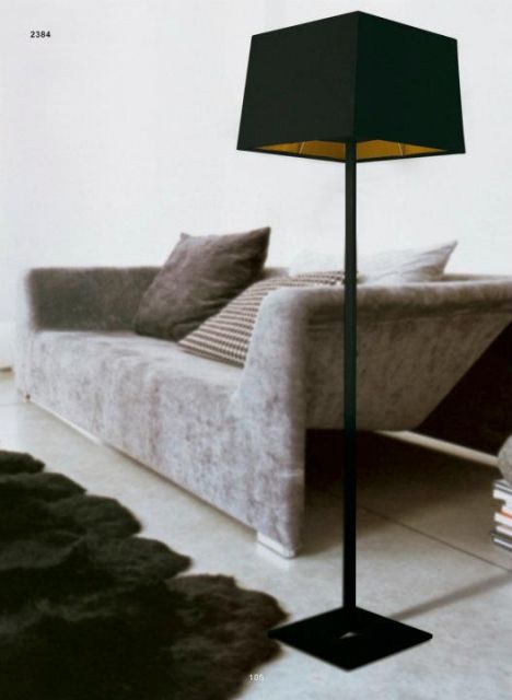 Sala com sofa cinza, luminaria abajour preta e tapete peludo no mesmo tom.