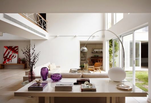 Sala clean nos tons de branco e madeira bege claro, com luminaria prata modelo arco.