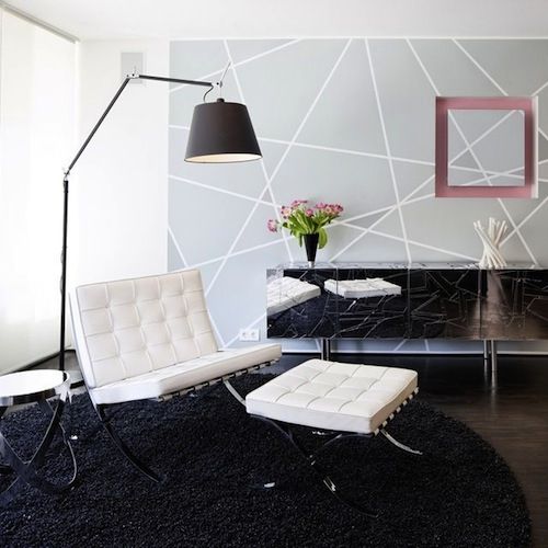 Sala com cadeira branca, tapete preto, e decoração cinza, com luminaria preta articular.