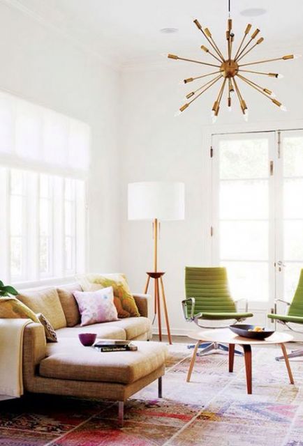 Sala clean com sofa bege, cadeiras verdes e luminaria de piso com tripe de madeira e cupula branca.