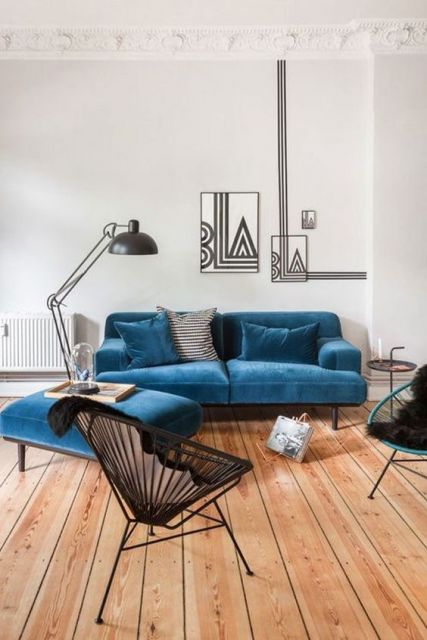 sofá de veludo azul com apoio de pé em ambiente minimalista