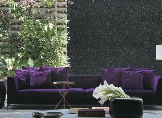 sofá de veludo roxo em sala com jardim vertical ao fundo
