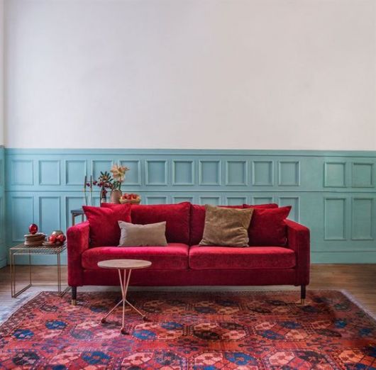 sofá de veludo vermelho com parede azul clara