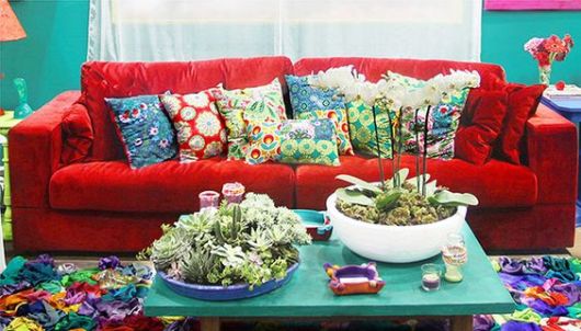 sofá de veludo vermelho com almofadas e móveis azuis