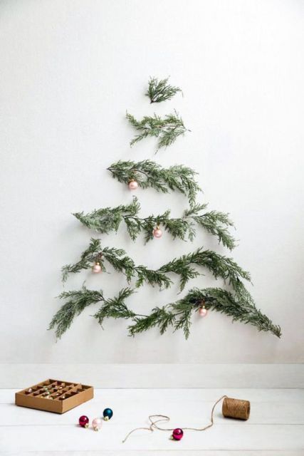árvore de Natal suspensa com folhas de pinheiro na parede