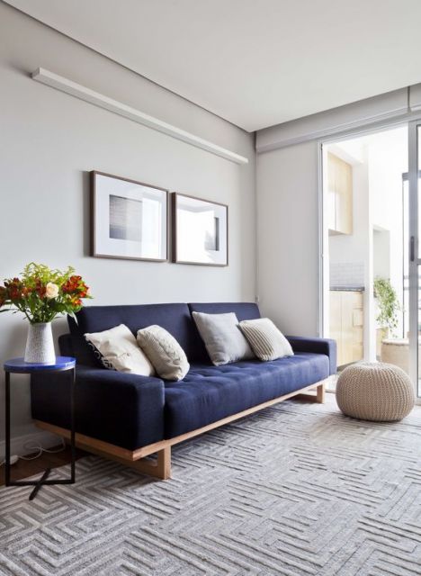 Sala com elementos neutros e sofá azul marinho.