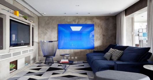 Sala com piso geométrico e sofa azul.