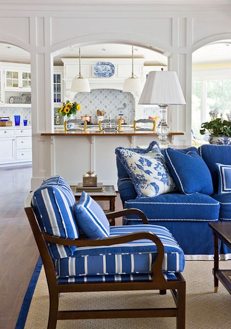Sala com sofá azul royal e poltronas com estampa de listras.