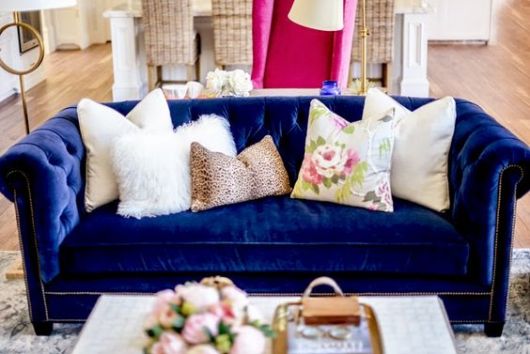 Sofá azul royal com almofadas claras.