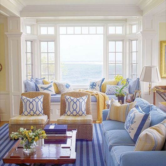 Sala com sofá azul e poltronas com tons neutros.
