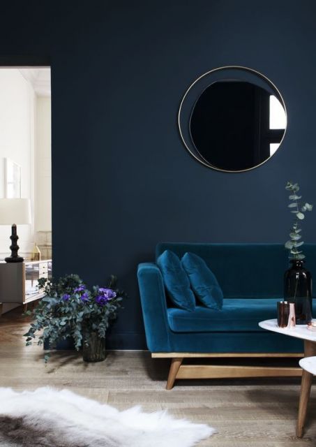 Sala com parede escura e sofá azul escuro.