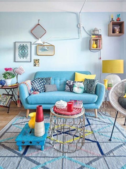 Sofá azul turqueza com almofadas e outros itens decorativos coloridos.