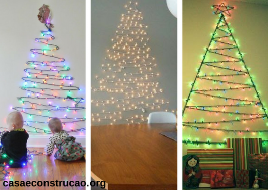 árvores de Natal diferentes feitas com luzinhas presas na parede