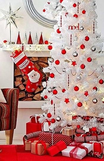 Meia pendurada na lareira e árvore de Natal branca com bolas vermelhas e prateadas.