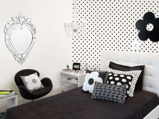 Modelo de quarto feminino preto e branco com almofadas divertidas.