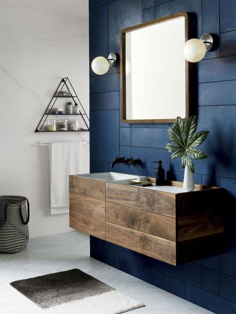 Banheiro pequeno azul marinho com gabinete marrom de madeira.