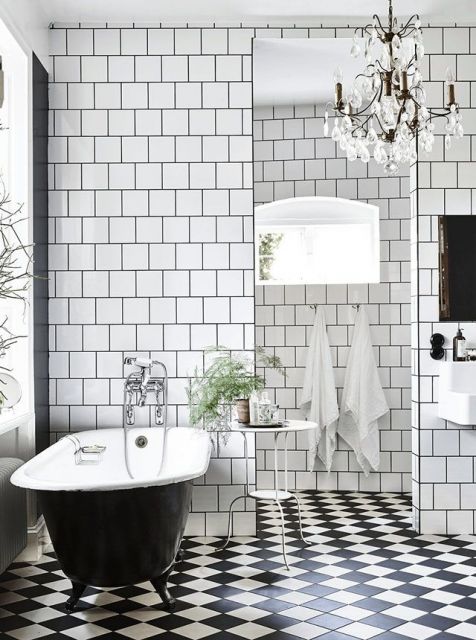 Banheiro pequeno com decoração preta e branca e lustre de cristais.