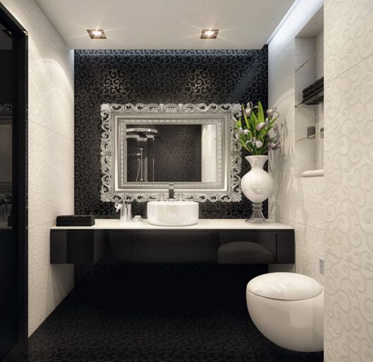 Banheiro pequeno preto e branco com espelho amplo moderno bisotado.