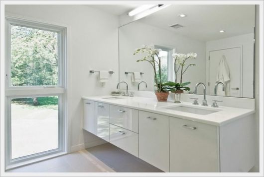 Modelo de banheiro branco com janela de vidro r pia gabinete larga.