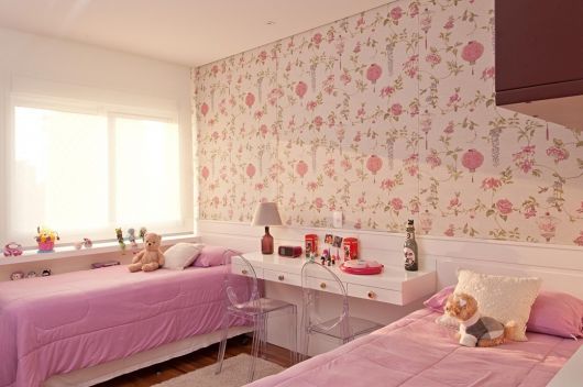 Quarto feminino infantil cor de rosa claro com papel de parede branco, rosa e lilás.