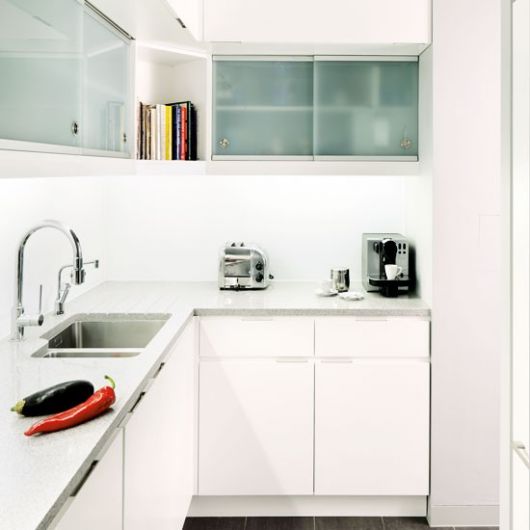 Modelo de cozinha branca pequena luminosa com armários de vidro.