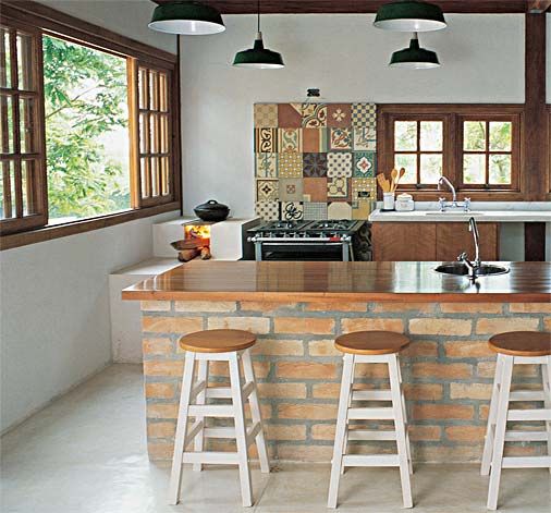 Cozinha rústica pequena com banquetas de madeira e balcão de tijolo a vista.