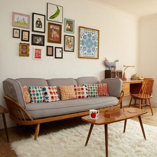 Modelo de sala com paredes claras, sofá com estofado cinza e mesinha de centro.