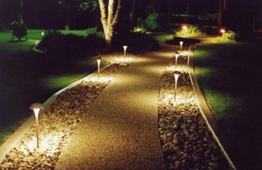 Caminho de um jardim composto por luminárias solares que estão acesas durante a noite. 