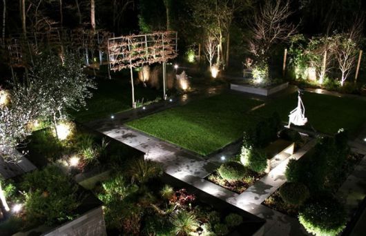 Foto mostrando um jardim inteiro composto por diversas plantas muito bem iluminadas com luminárias solares.