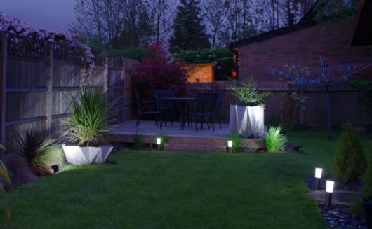 Jardim espaçoso com algumas luminárias solares pequenas posicionadas nos cantos para iluminação. 