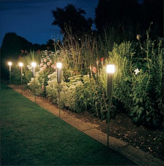 luminárias solares instaladas no chão de um jardim com uma altura considerável. 