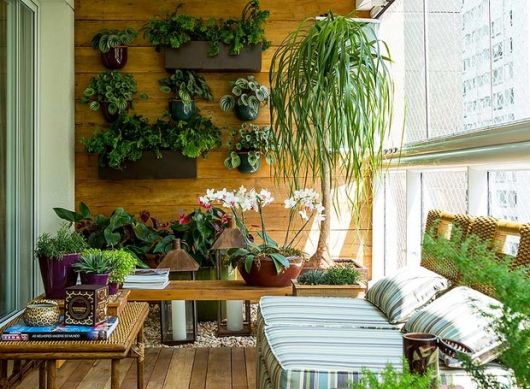 Foto de uma varanda gourmet decorada com muitas plantas, tanto nas parede quanto em vasos no chão. 