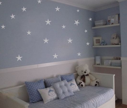 Quarto de bebê com parede azul com estrelas.