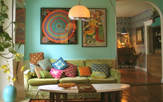 Sala na cor azul turquesa, com sofá verde e almofadas coloridas.