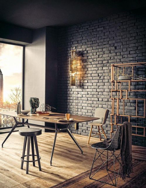 Sala de jantar com mesa de madeira e matal, paredes tijolo a vista cinza e cadeiras estilo banquetas.