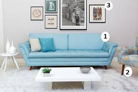 Modelo de sofá azul claro com sala de quadros grandes e sofá azul bem clarinho.