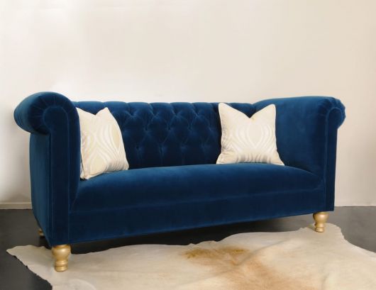 Sala com paredes em tons pastéis lisa com sofá azul marinho e almofadas claras.