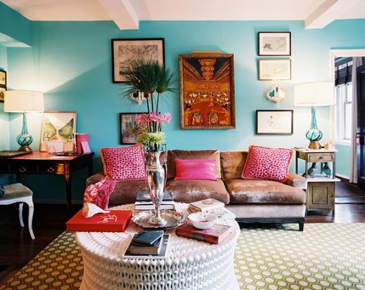 Sala azul com quadros antigos e sofá marrom de três lugares.