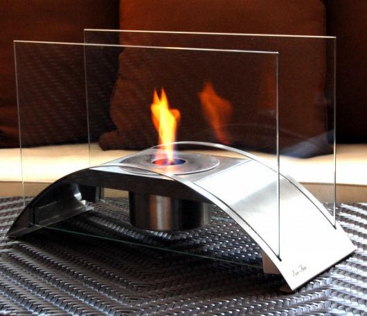 Lareira ecológica portátil pequena acesa com a chama sendo protegida por dois vidros laterais. 