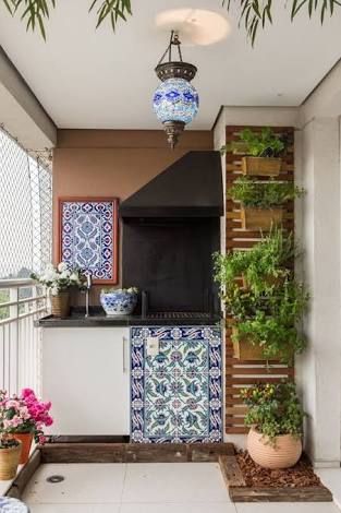 Churrasqueira na varanda, com tijolos azuis e plantas penduradas.