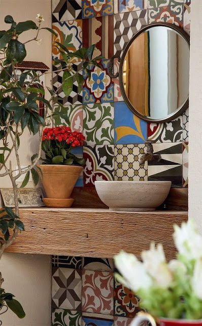 Pequena bancada de madeira em um banheiro posicionada em frente a uma parede com azulejos portugueses coloridos. 