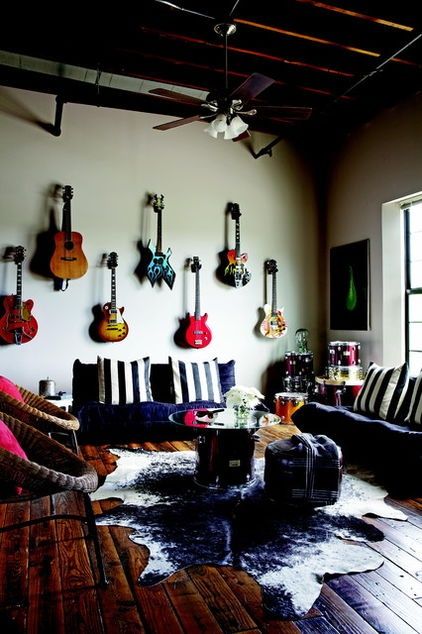 Sala de estar com uma mesa de centro cuja base é uma parte de bateria e a parede tem vários instrumentos musicais pendurados. 