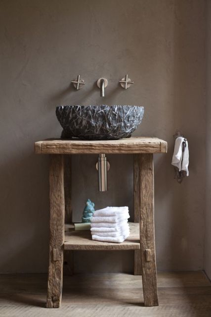 Foto de uma bancada feita de madeira e uma torneira de lavabo de parede com duas aberturas. 