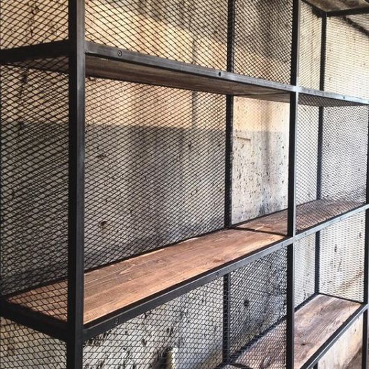 Foto em close up de uma estante com as extremidades feitas em aço e a parte interna feita com madeira. 