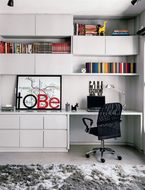 Ambiente de Home Office com mesa e estantes em MDF onde são colocados livros, objetos de decoração e um notebook em frente a uma cadeira. 