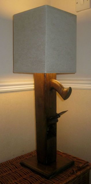Foto de uma luminária com a lâmpada coberta por uma espécie de papel branco e a base feita a partir de madeira. 