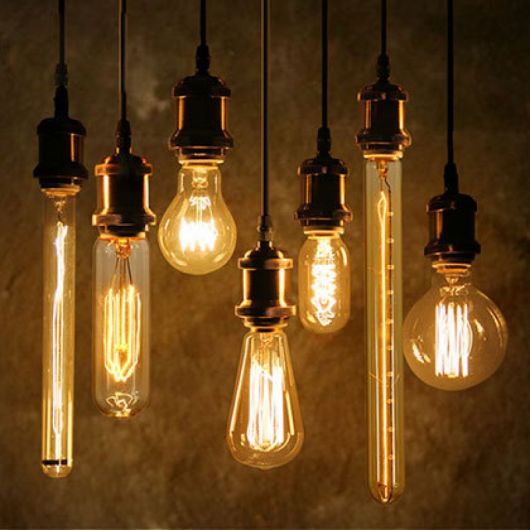 Foto de diversas lâmpadas penduradas no teto por fios com formatos de todos os tipos. 